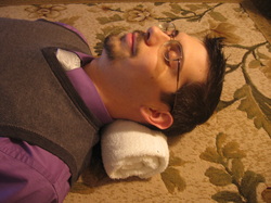 How to lay on the rolled towel for neck and headache relief.